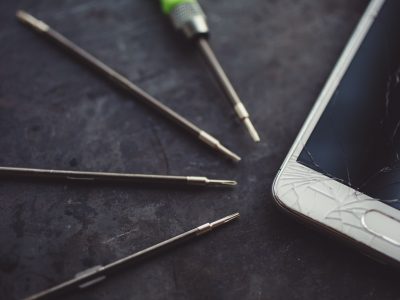 Smartphone with a broken screen and repair tools.